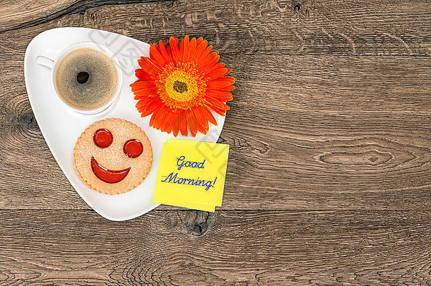 带微笑饼干和雏菊花的咖啡。有趣的早餐。样本文本早上好！