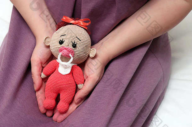 床上坐着一个带着<strong>针</strong>织娃娃的女人。怀孕、孕产、不孕、、生育的概念