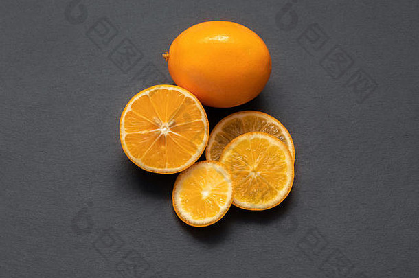 在石桌上切成片的柑橘类水果。食物背景。平铺。成熟多汁的橙子片，柠檬片，柑橘片，灰色背景。俯视图关闭
