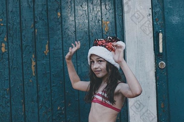 一个孩子正在玩圣诞老人的帽子。夏天，戴着圣诞老人帽子的小女孩在户外。新年还是圣诞节
