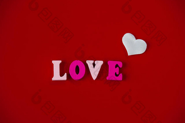 爱的概念——红色背景的木制字母和红心中的“爱”一词