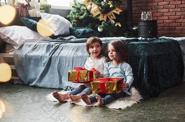 今天有人得到了他们的礼物。这两个孩子坐在室内靠近床的漂亮房间里，圣诞假期<strong>有礼</strong>物<strong>送</strong>给他们