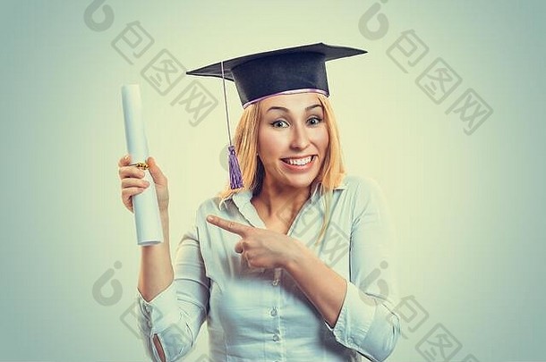 肖像特写美丽的微笑快乐欣喜若狂的研究生毕业学生戴帽子的金发女郎指着<strong>展示</strong>文凭<strong>卷轴</strong>绿色背景