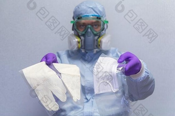 一名身穿防护服的男子展示并提供了一个医用口罩和手套，用于个人防病毒-健康和医学概念，pr