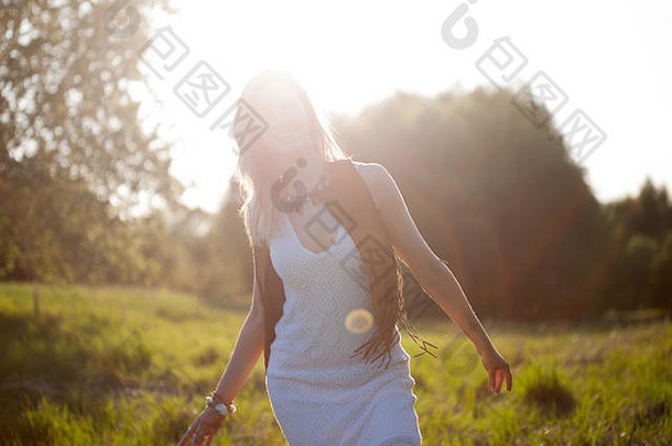 可爱迷人的女孩在夏天的田野里。这位年轻女子在户外很快乐，感觉很自由。夏天，走在田野上，<strong>阳光</strong>耀眼。