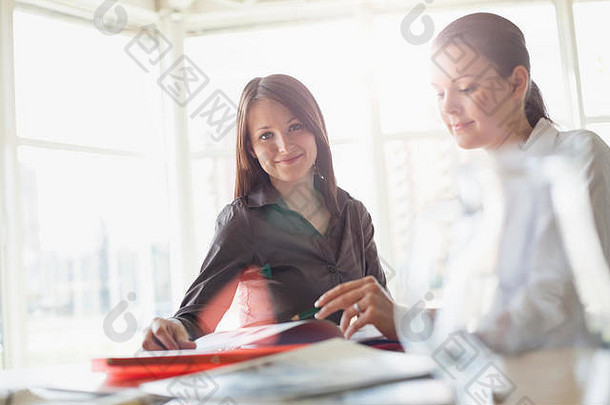 年轻女商人与女同事在办公桌上讨论的照片