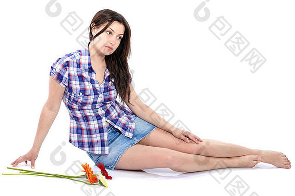 穿着格子衬衫的漂亮年轻女子坐在地板上，手里拿着非洲菊花