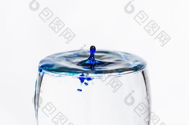 蓝色水滴溅入一杯清澈的水中