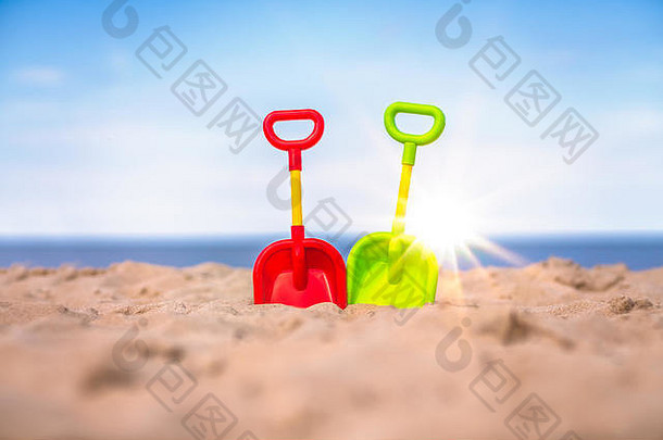 在美丽的白色沙滩上，有两个红、黄、绿三色的儿童沙滩玩具