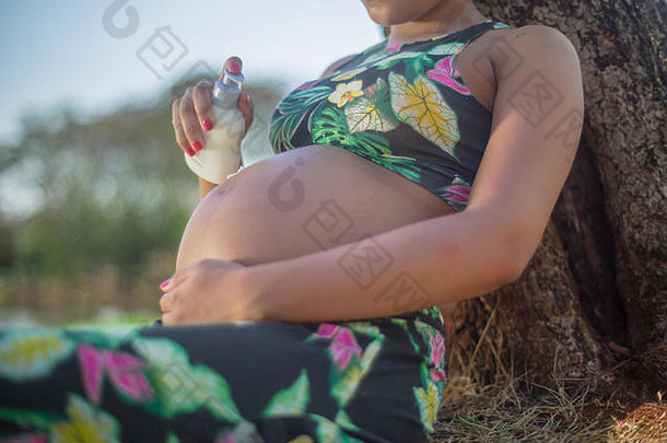 公园里的孕妇在腹部涂上乳霜以避免妊娠纹。