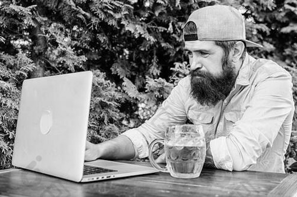 使用新技术。胡子男人通过通讯技术进行通讯。时髦人士在户外咖啡馆喝啤酒和使用笔记本电脑技术。利用计算机技术保持生产力。