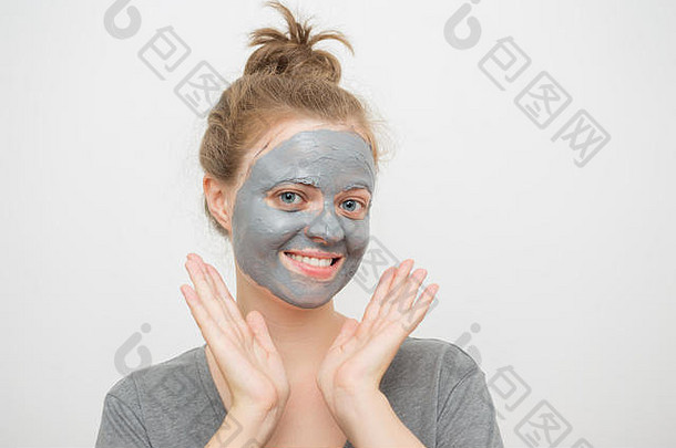 年轻的白人妇女，脸上带着黑色或灰色的泥质面膜，面带微笑