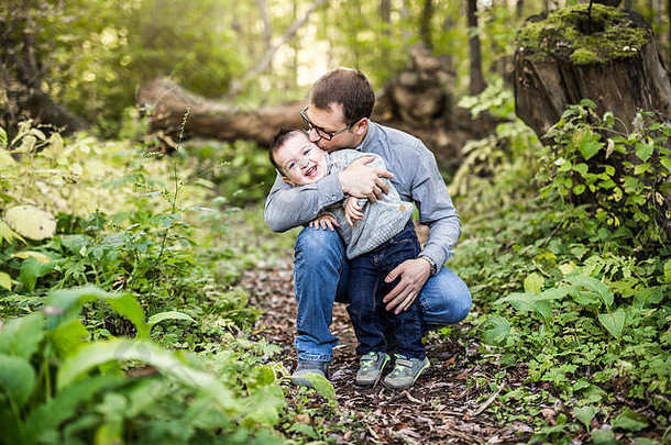 小男孩和他的父亲在秋林的草地上
