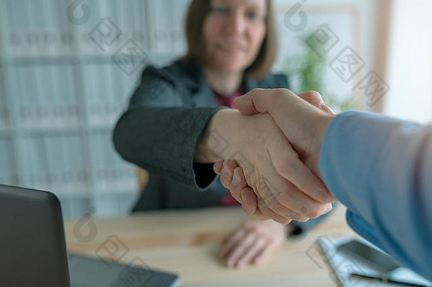 商人和女商人握手，两位商人握手并互相问候，公司会议开始在办公室举行