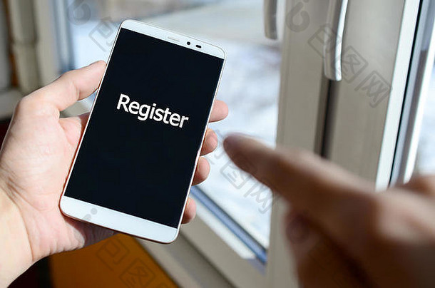 一个人在手里拿着的黑色智能手机显示屏上看到一个白色的铭文。登记