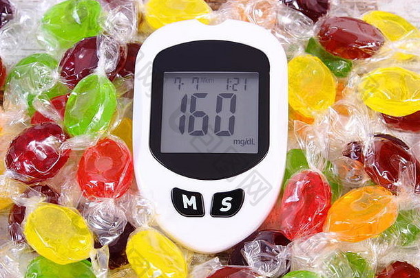 血糖仪测量血糖水平和成堆彩色糖果的不良结果，糖尿病的概念，健康的生活方式