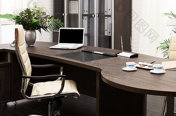 在现代办公室里，桌上放着笔记本电脑和鲜花