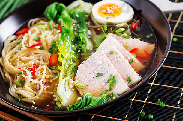 味噌拉面亚洲面条，碗中有鸡蛋、猪肉和白菜，背景为深色。日本料理。