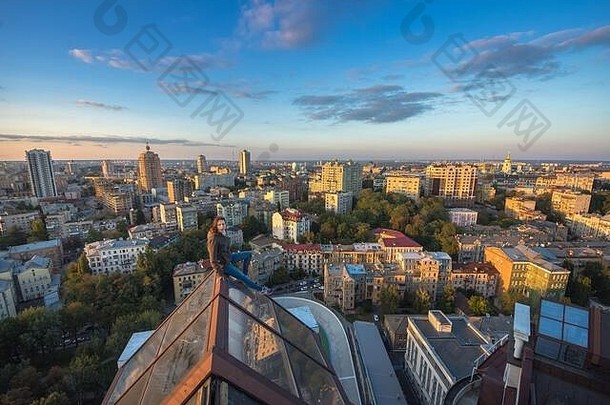 乌克兰基辅，坐在现代化建筑屋顶上的女人。在基辅市的屋顶上攀爬的极限<strong>女孩</strong>。Kie屋顶上的日落时间