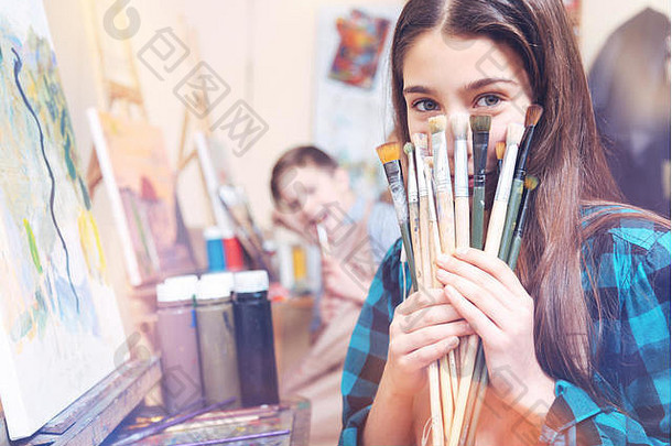 漂亮的年轻女士展示着一堆旧画笔