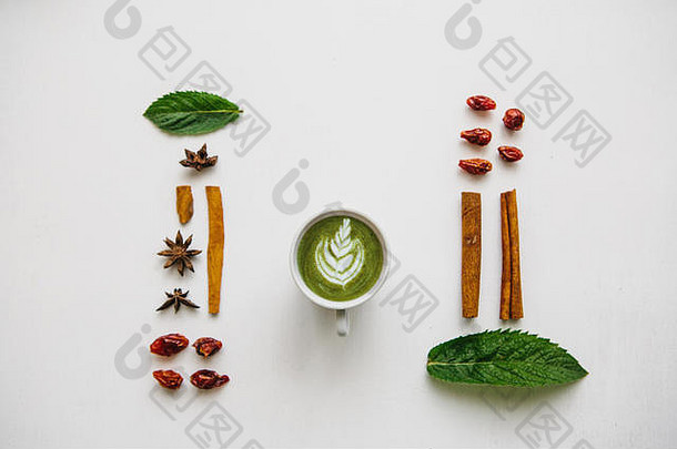 将一杯新鲜有用的绿抹茶拿铁咖啡平铺在白色表面上，并加入各种配料。