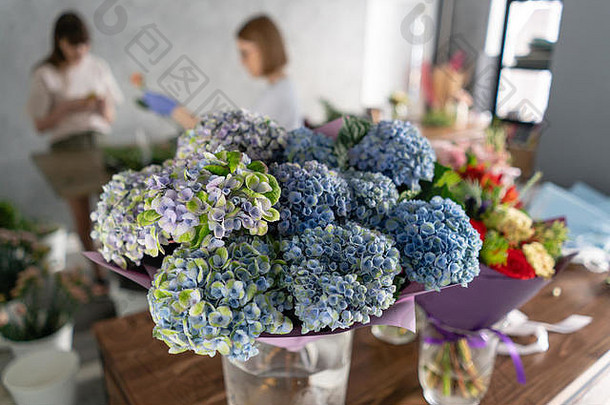 前景是一家花店背景上的花瓶。人们工作，职业花匠。夏日花束。送花