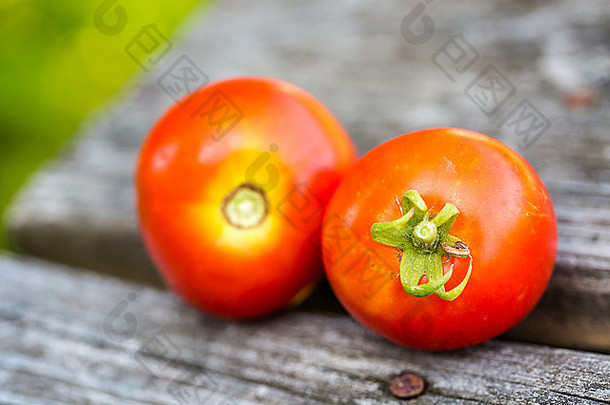 木凳上放着两个成熟的红色西红柿。