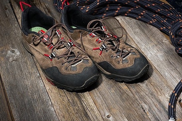 木制背景上有绳子的登山鞋