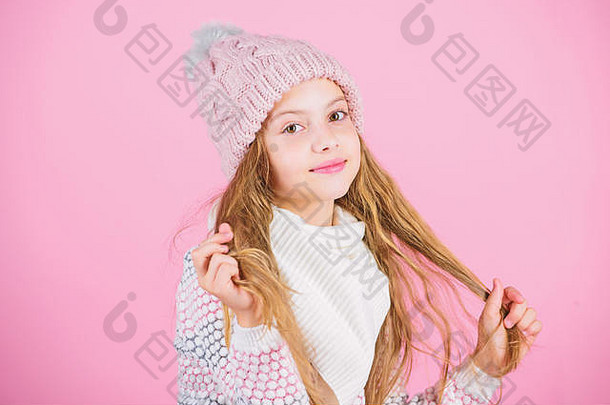 孩子长发微笑。女孩戴着粉色背景的针织帽子。防止冬季头发损伤。冬季护发贴士你一定要遵循。冬季训练你自己，让自己在洗漱之间保持更长的时间。