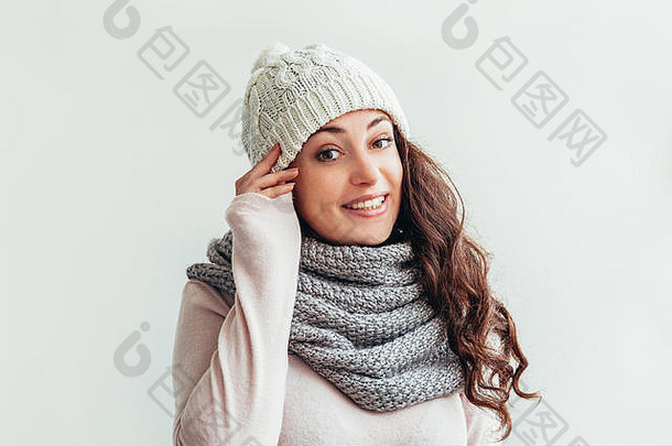 美丽的女人冬季肖像，真实的情感。留着长发的笑女孩，穿着保暖的衣服，戴着帽子，围巾，白色背景。年轻的时髦女孩看起来快乐、兴奋，玩得很开心