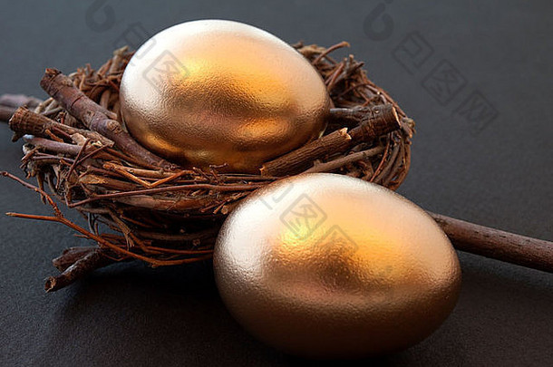 一对金鸡蛋坚固的巢成功的投资图片黑色的背景