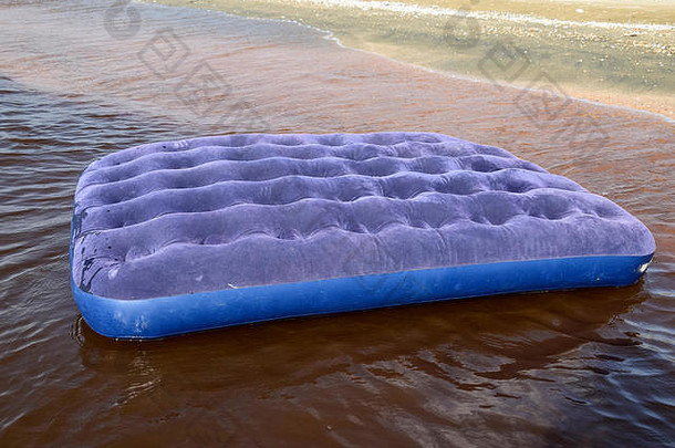 蓝色充气床垫在池塘里游泳。海滩上的充气床垫。