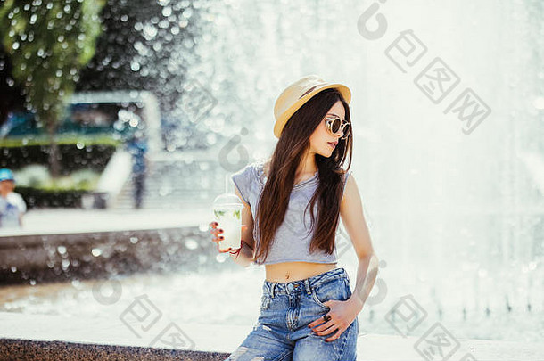 微笑积极的有趣的年轻的女人持有杯喝阳光户外街风格