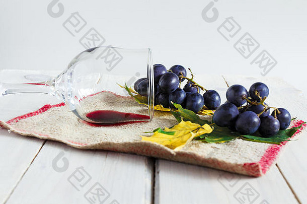 质朴的设置，一杯<strong>干红葡萄酒</strong>，葡萄和秋天的叶子上的纹理织物