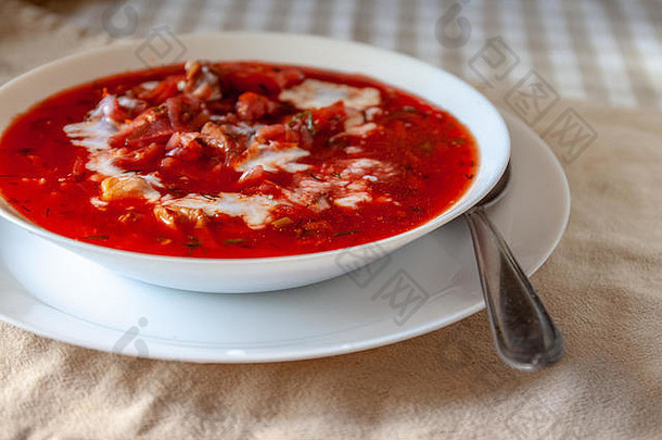 传统的乌克兰-俄<strong>罗</strong>斯番茄<strong>罗宋汤</strong>配酸奶油，放在桌上的白色盘子里。从上面看。