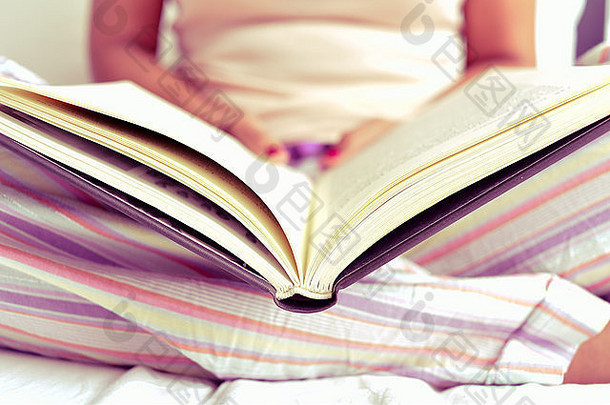 特写镜头年轻的高加索人女人睡衣阅读书床上