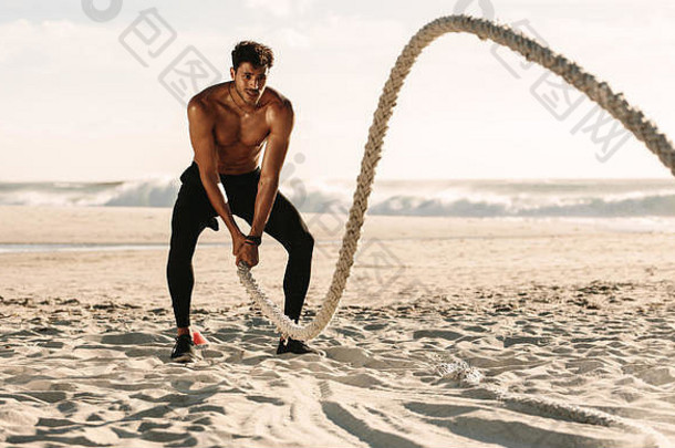 男人。健身锻炼海滩阳光明媚的一天只胸的男人。锻炼战斗绳子海滩