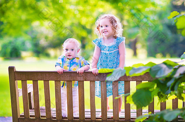 可爱的孩子们，小卷发女孩和可爱的，兄弟姐妹，一起坐在花园里的木凳上