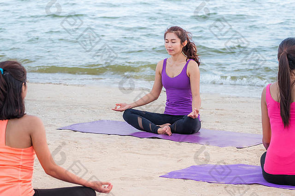 傍晚日落时分在海边上瑜伽课，一群亚洲人在海滩上用蛤蜊做莲花式放松情绪，冥想式，<strong>身心健康</strong>