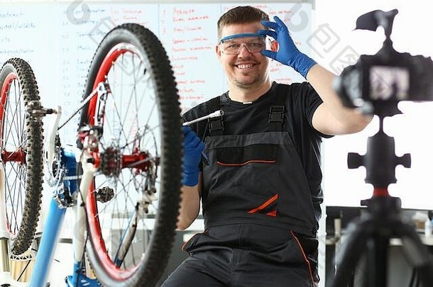 快乐的男人调整安全眼镜，坐在自行车旁边