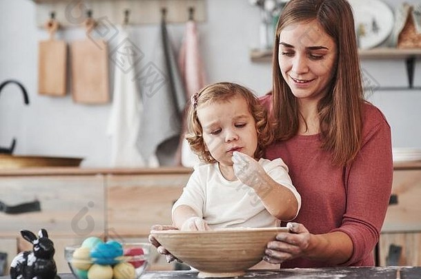 不，你还不能吃。母亲教女儿画复活节的彩蛋