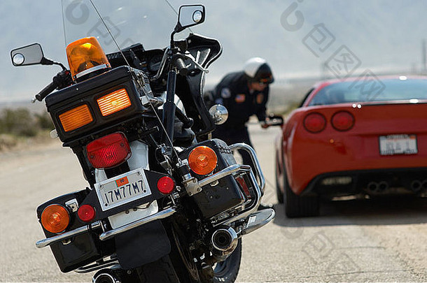 <strong>交警</strong>与跑车司机交谈，关注前景中的摩托车