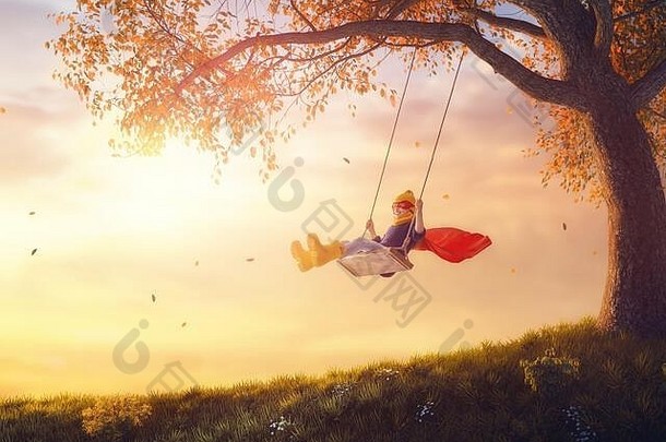 落日秋千上快乐的孩子。孩子们在秋天的自然漫步中玩耍。穿超级英雄服装的女孩。
