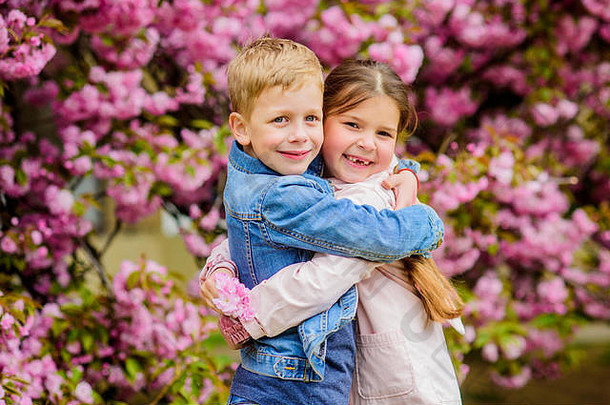 浪漫的婴儿。两个孩子在樱花树花园散步。温柔的爱情。小女孩和男孩。浪漫的约会。春天是坠入爱河的时候。恋爱中的孩子粉色樱花。爱在空气中。