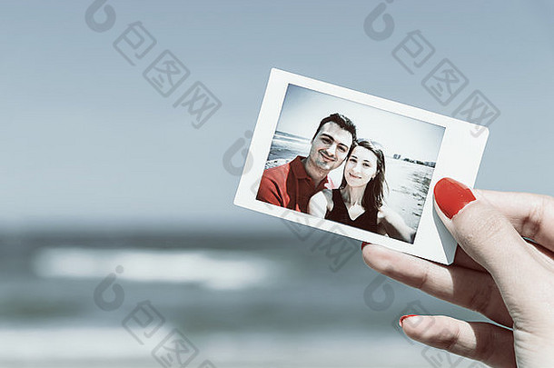女孩手握着海滩上年轻幸福夫妇的复古即时照片