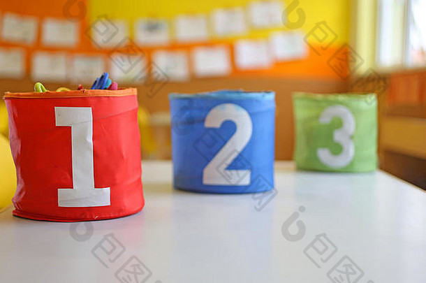 幼儿园教室的桌子上有三个红、绿、蓝相间的罐子，上面写着“一、二、三”
