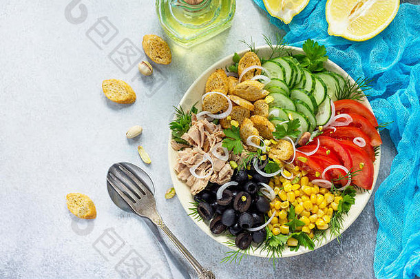 夏季沙拉配醋醋沙拉酱。色拉配金鱼、新鲜蔬菜、开心果和绿色蔬菜，背景为灰色石头或石板。顶视图。