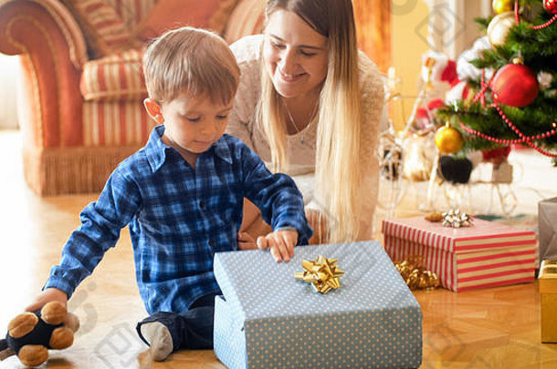 可爱的小男孩打开并看着圣诞礼品盒里面