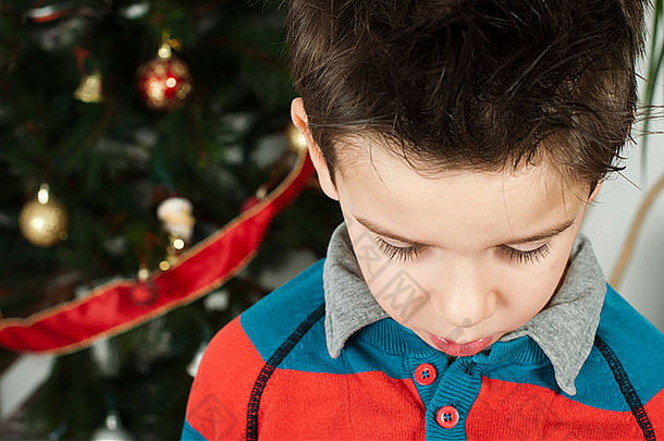 圣诞弥撒上<strong>不</strong>幸的小男孩。背景中的圣诞树