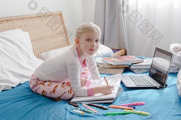 白人女孩坐在床上通过笔记本电脑上<strong>网</strong>学习。在家中自我隔离<strong>期间</strong>的视频虚拟<strong>课</strong>程。远程